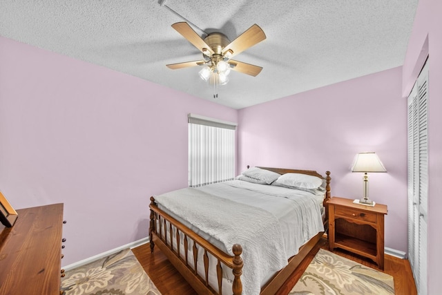 bedroom with a textured ceiling, a closet, hardwood / wood-style flooring, and ceiling fan