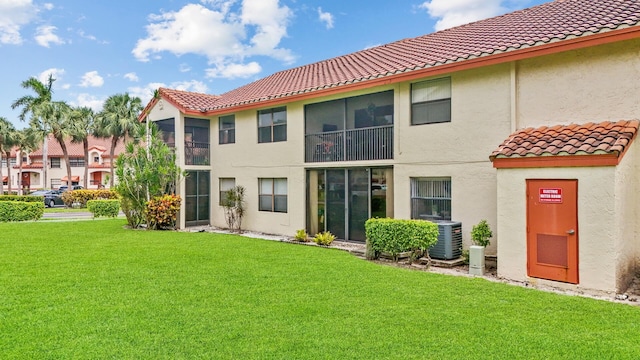 rear view of property featuring central AC and a lawn