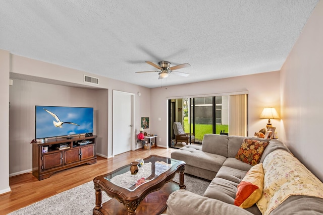 living room with ceiling fan, light hardwood / wood-style floors, and a textured ceiling