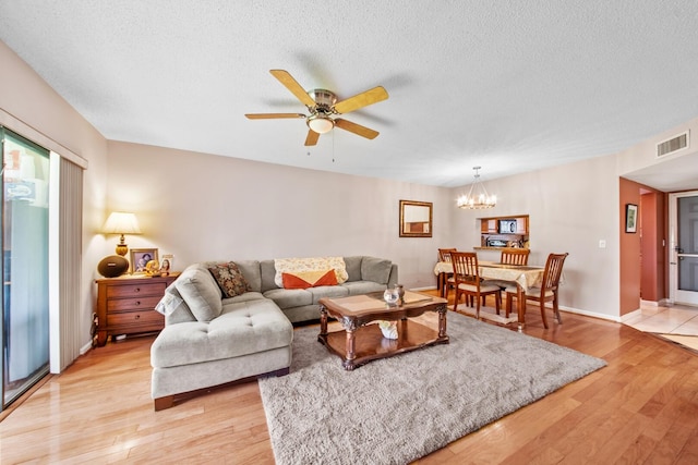 living room featuring a textured ceiling, light hardwood / wood-style floors, and ceiling fan with notable chandelier