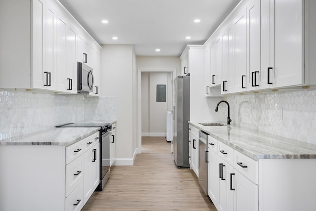 kitchen featuring white cabinets, appliances with stainless steel finishes, light stone countertops, light wood-type flooring, and sink