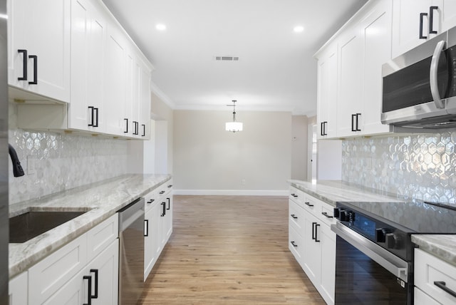 kitchen with white cabinets, hanging light fixtures, backsplash, light hardwood / wood-style flooring, and stainless steel appliances