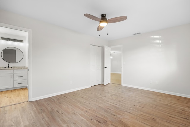 unfurnished bedroom with sink, light hardwood / wood-style flooring, ensuite bathroom, and ceiling fan