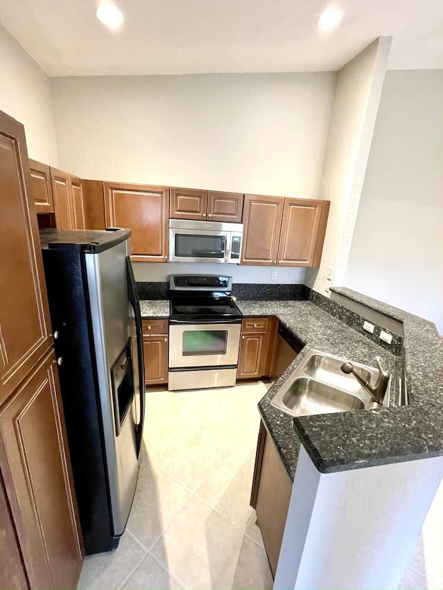 kitchen featuring sink, kitchen peninsula, stainless steel appliances, and dark stone counters