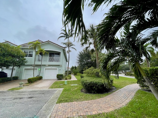 exterior space featuring a front yard, a balcony, and a garage