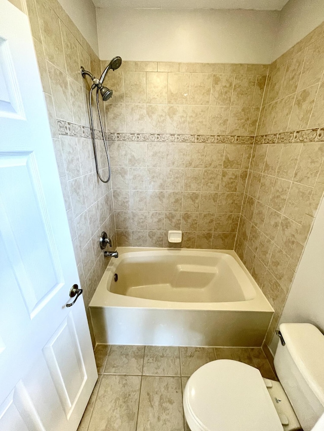 bathroom with toilet, tiled shower / bath combo, and tile patterned floors