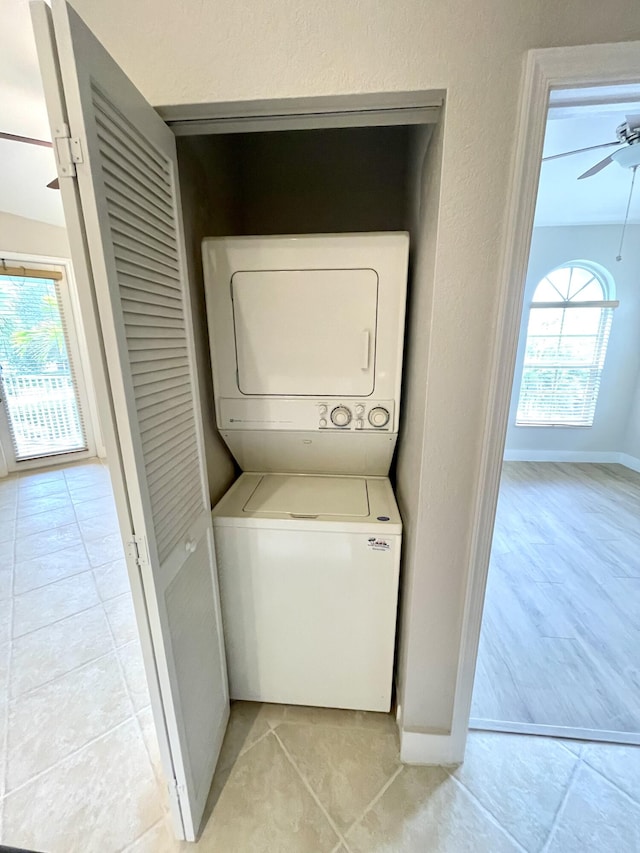 clothes washing area with stacked washer / drying machine, ceiling fan, and light tile patterned floors