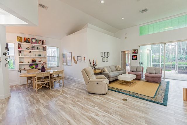 living room with high vaulted ceiling and light wood-type flooring