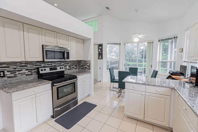 kitchen with light tile patterned floors, white cabinetry, backsplash, stainless steel appliances, and light stone countertops