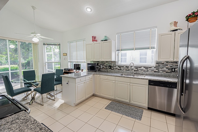 kitchen with sink, stainless steel appliances, light tile patterned flooring, decorative backsplash, and kitchen peninsula