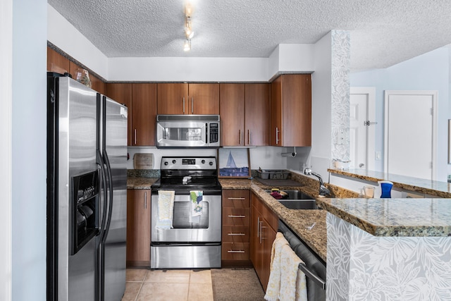 kitchen with sink, a textured ceiling, kitchen peninsula, stainless steel appliances, and light tile patterned floors