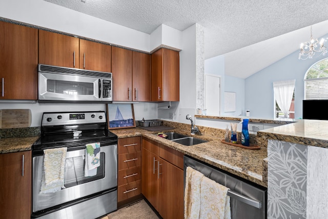 kitchen with an inviting chandelier, vaulted ceiling, dark stone countertops, sink, and stainless steel appliances