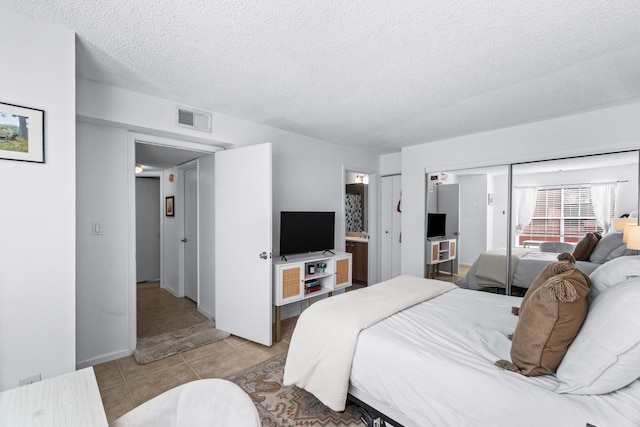 bedroom featuring a closet, a textured ceiling, and light tile patterned floors