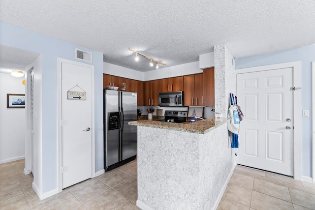 kitchen featuring kitchen peninsula, light tile patterned floors, appliances with stainless steel finishes, light stone counters, and a textured ceiling