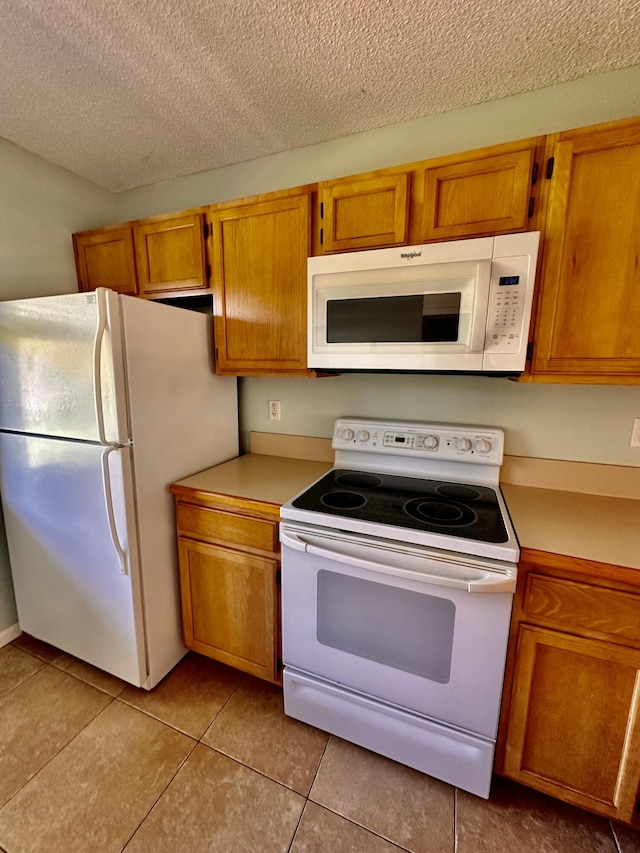 kitchen with white appliances, a textured ceiling, and light tile patterned floors