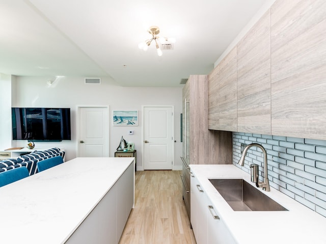 kitchen featuring white cabinetry, decorative backsplash, light hardwood / wood-style floors, and sink