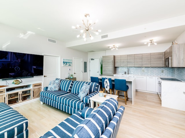 living room with light hardwood / wood-style floors, sink, and an inviting chandelier