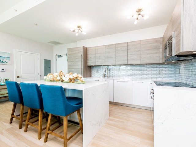 kitchen featuring light hardwood / wood-style flooring, white cabinetry, a kitchen breakfast bar, and a center island