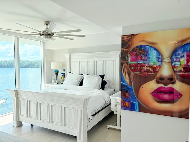 bedroom featuring access to outside, a water view, and hardwood / wood-style floors