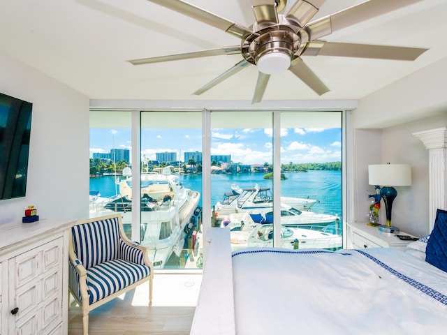 bedroom with hardwood / wood-style flooring, ceiling fan, multiple windows, and a water view