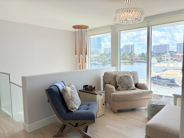 sitting room featuring a water view, a notable chandelier, and light hardwood / wood-style floors