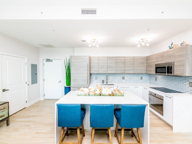 kitchen with stainless steel appliances, light hardwood / wood-style floors, a center island, sink, and a breakfast bar