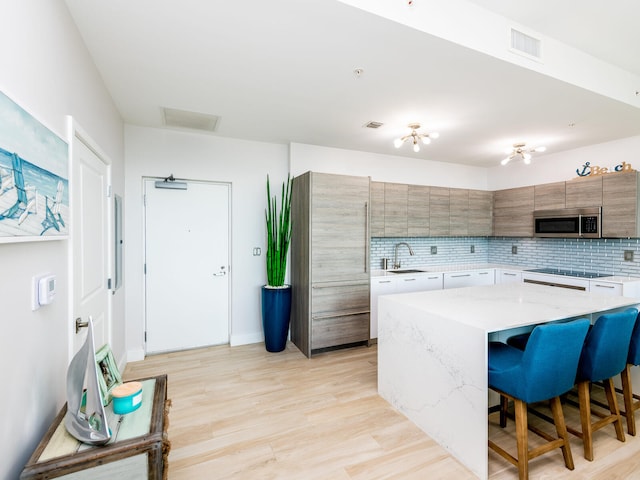 kitchen with a kitchen breakfast bar, backsplash, light hardwood / wood-style flooring, a kitchen island, and white cabinets