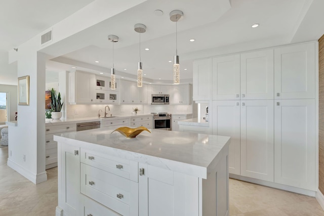 kitchen with a kitchen island, sink, pendant lighting, white cabinetry, and appliances with stainless steel finishes