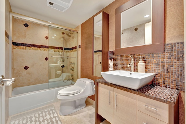 full bathroom featuring toilet, enclosed tub / shower combo, tile walls, vanity, and decorative backsplash