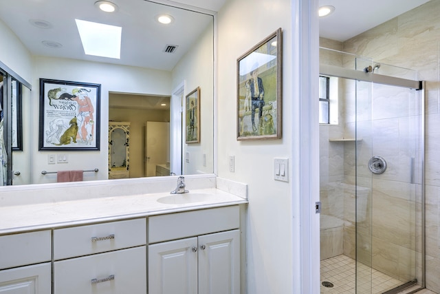 bathroom featuring vanity, an enclosed shower, and a skylight