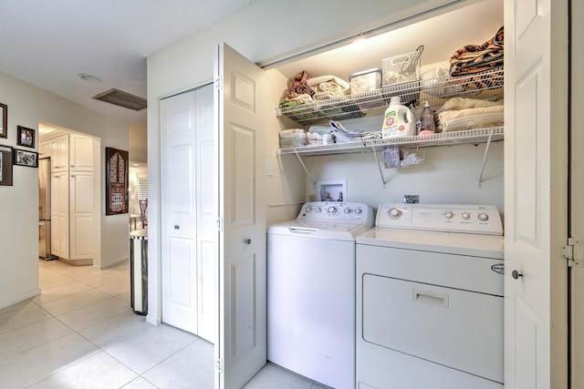 clothes washing area with washing machine and dryer and light tile patterned floors