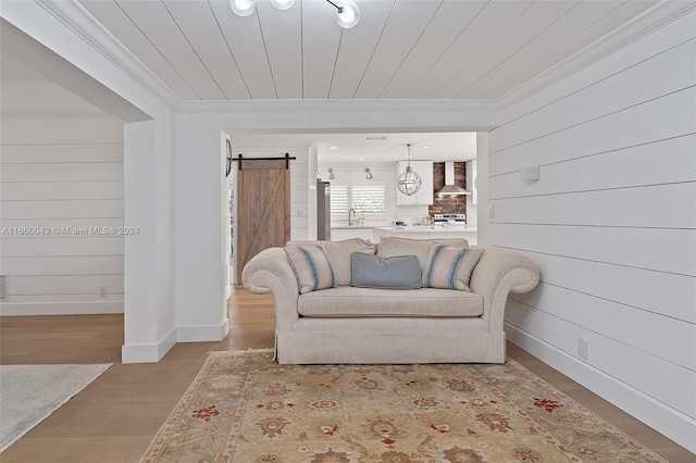 sitting room with sink, light hardwood / wood-style flooring, wooden walls, and a barn door