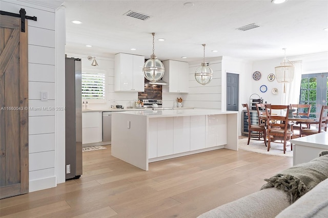 kitchen with white cabinetry, a barn door, a center island, and plenty of natural light