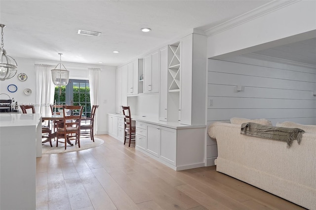 dining area featuring a notable chandelier, ornamental molding, and light wood-type flooring