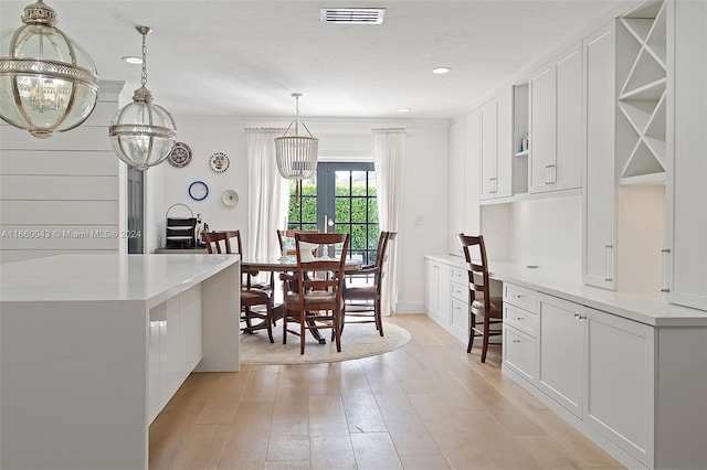 kitchen with white cabinetry, pendant lighting, a notable chandelier, and light wood-type flooring