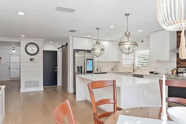 kitchen featuring a notable chandelier, a kitchen island, a barn door, and white cabinets