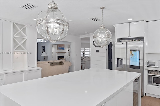 kitchen with white cabinets, light hardwood / wood-style flooring, ornamental molding, pendant lighting, and stainless steel appliances