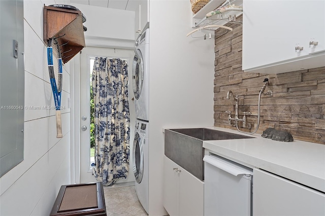 clothes washing area with stacked washer and dryer, sink, and light tile patterned floors