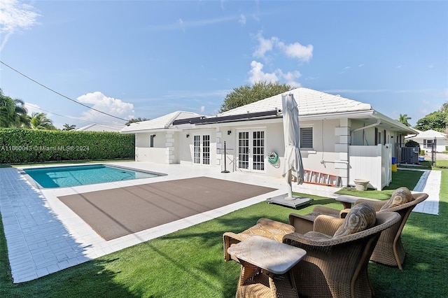 back of property featuring a fenced in pool, french doors, a patio, and a lawn