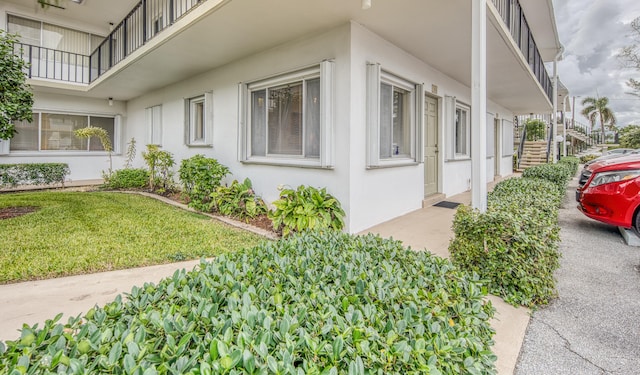 view of side of property featuring a yard and a balcony