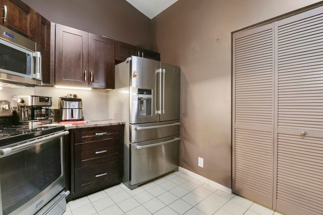 kitchen featuring stainless steel appliances, light tile patterned floors, and dark brown cabinetry