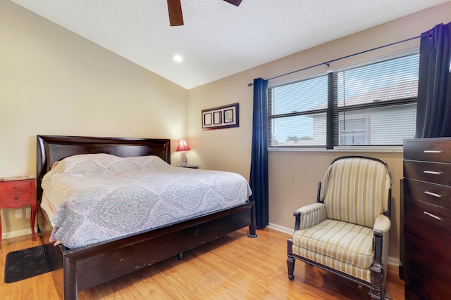 bedroom with ceiling fan, light hardwood / wood-style floors, and vaulted ceiling