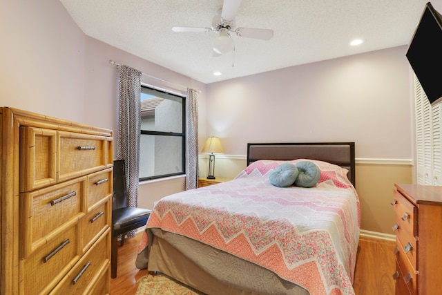 bedroom featuring light wood-type flooring, a textured ceiling, and ceiling fan