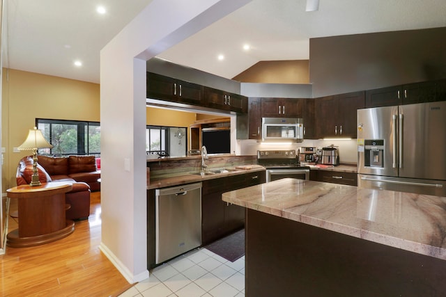 kitchen with light tile patterned flooring, high vaulted ceiling, sink, stainless steel appliances, and dark brown cabinets