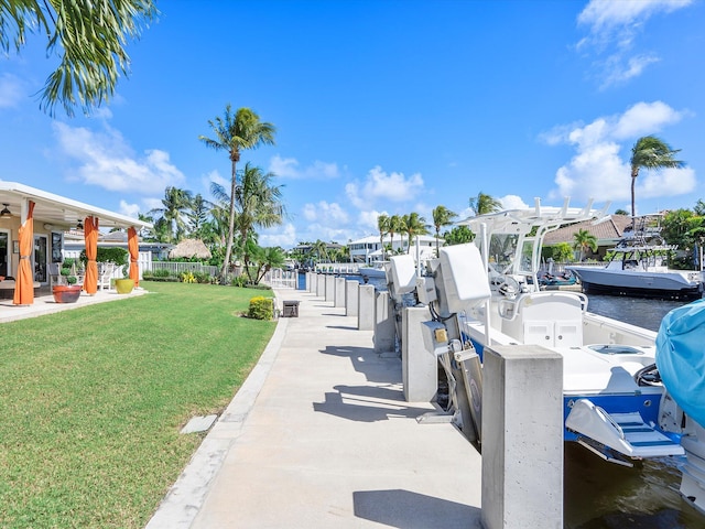 dock area featuring a water view, a patio, and a yard