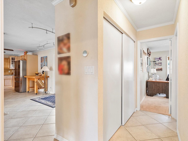 corridor featuring crown molding, rail lighting, sink, and light tile patterned floors