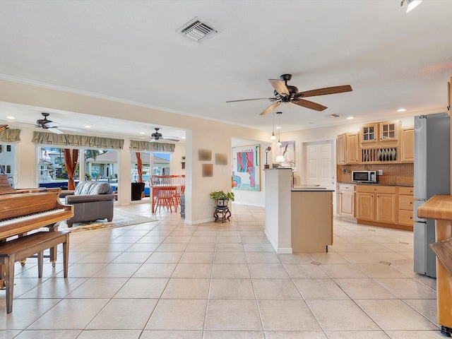 kitchen featuring light brown cabinetry, ornamental molding, appliances with stainless steel finishes, and light tile patterned floors