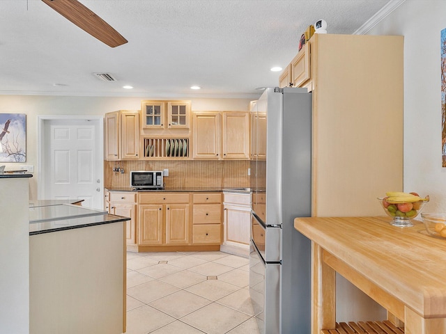 kitchen with light brown cabinets, tasteful backsplash, ceiling fan, stainless steel refrigerator, and crown molding