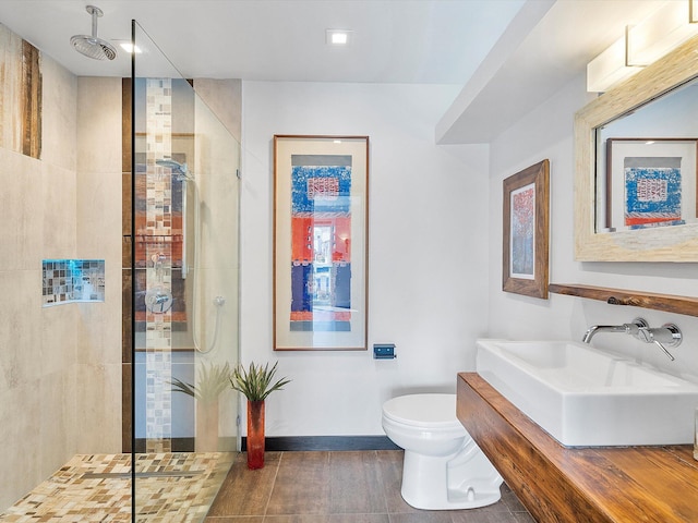 bathroom with vanity, a tile shower, toilet, and tile patterned floors