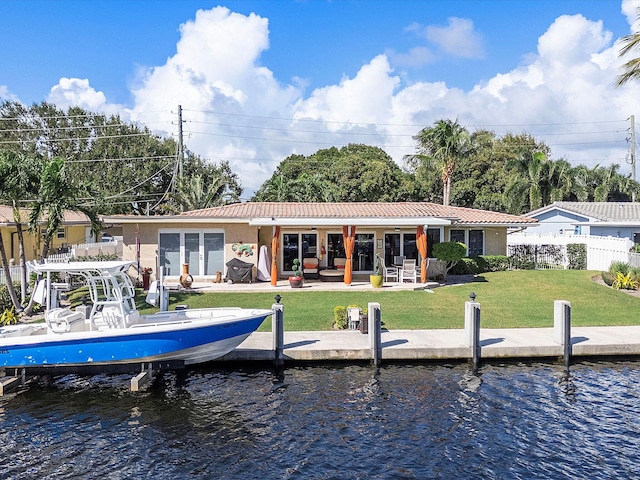 back of house featuring a patio area, a yard, and a water view